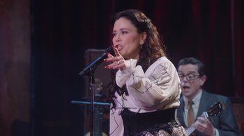 Movie still from “Alex Borstein: Corsets & Clown Suits” (2023), directed by Scott Ellis – A woman holding a microphone while standing in front of a crowd; Medium shot, Over the shoulder angle
