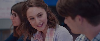 Movie still from “Alex Strangelove” (2018), directed by Craig Johnson – A young woman smiles at the camera while a young man looks at her; Close Up shot, Over the shoulder angle