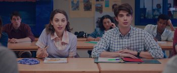 Movie still from “Alex Strangelove” (2018), directed by Craig Johnson – Two people sitting at a table in a classroom; Medium shot, Over the shoulder angle