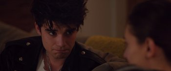 Movie still from “Alex Strangelove” (2018), directed by Craig Johnson – A man with a black jacket and a black wig; Close Up shot, Over the shoulder angle