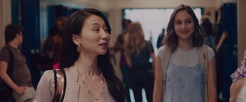 Movie still from “Alex Strangelove” (2018), directed by Craig Johnson – A woman standing next to another woman in front of a group of people; Close Up shot, Over the shoulder angle