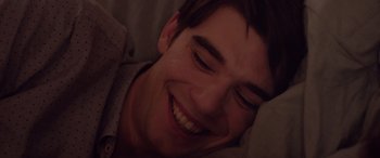 Movie still from “Alex Strangelove” (2018), directed by Craig Johnson – A person smiling with his eyes closed; Close Up shot, Overhead angle