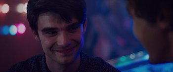 Movie still from “Alex Strangelove” (2018), directed by Craig Johnson – A person smiling at the camera; Close Up shot, Over the shoulder angle
