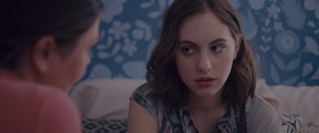 Movie still from “Alex Strangelove” (2018), directed by Craig Johnson – A woman sitting on a couch looking at another woman; Close Up shot, Over the shoulder angle