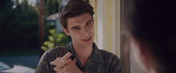 Movie still from “Alex Strangelove” (2018), directed by Craig Johnson – A young man holding a cell phone in his hand; Close Up shot, Over the shoulder angle