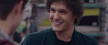 Movie still from “Alex Strangelove” (2018), directed by Craig Johnson – A person with curly hair smiling; Close Up shot, Over the shoulder angle