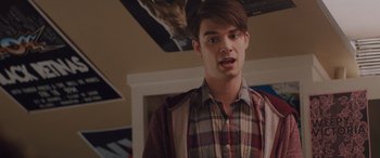 Movie still from “Alex Strangelove” (2018), directed by Craig Johnson – A young man in a plaid shirt is standing in a room; Close Up shot, Over the shoulder angle