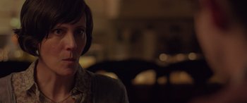 Movie still from “Alex Strangelove” (2018), directed by Craig Johnson – A woman with short brown hair wearing a jacket; Close Up shot, Over the shoulder angle