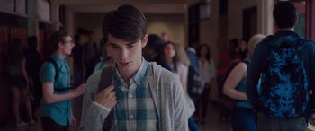 Movie still from “Alex Strangelove” (2018), directed by Craig Johnson – A young man is standing in front of a group of people; Medium shot, Over the shoulder angle