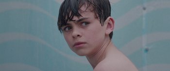 Movie still from “Alex Strangelove” (2018), directed by Craig Johnson – A young boy with wet hair is looking into the camera; Close Up shot, Over the shoulder angle