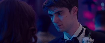 Movie still from “Alex Strangelove” (2018), directed by Craig Johnson – A man in a suit and bow tie looking at a woman in a dress; Close Up shot, Over the shoulder angle