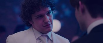 Movie still from “Alex Strangelove” (2018), directed by Craig Johnson – A man in a white suit and a white tie; Close Up shot, Over the shoulder angle