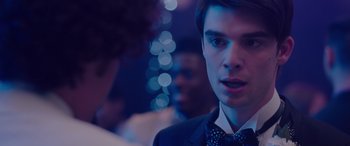 Movie still from “Alex Strangelove” (2018), directed by Craig Johnson – A man in a suit and bow tie talking to another man in a suit and bow tie; Close Up shot, Over the shoulder angle