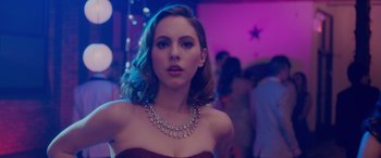 Movie still from “Alex Strangelove” (2018), directed by Craig Johnson – A beautiful young lady wearing a dress and a necklace; Close Up shot, Over the shoulder angle