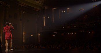 Movie still from “Ali Wong: Don Wong” (2022), directed by Nahnatchka Khan – A crowd of people sitting in a dark room at night; Extreme Wide shot, Low angle