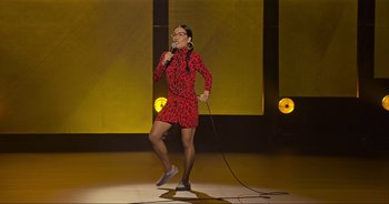 Movie still from “Ali Wong: Don Wong” (2022), directed by Nahnatchka Khan – A woman in a red and black dress holding a microphone on a stage; Extreme Wide shot, High angle