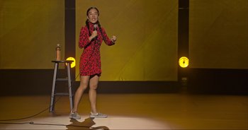 Movie still from “Ali Wong: Don Wong” (2022), directed by Nahnatchka Khan – A woman standing on a stage holding a microphone; Wide shot, Over the shoulder angle