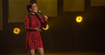 Movie still from “Ali Wong: Don Wong” (2022), directed by Nahnatchka Khan – A woman in a red dress holding a microphone on a stage; Medium shot, High angle