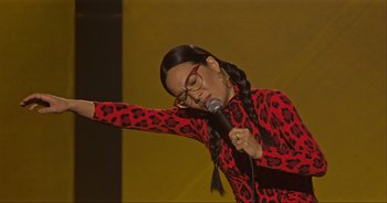 Movie still from “Ali Wong: Don Wong” (2022), directed by Nahnatchka Khan – A woman in a red leopard print outfit holding a microphone; Medium shot, High angle