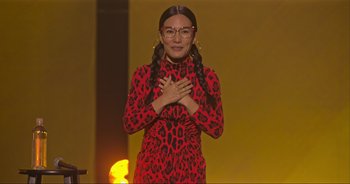 Movie still from “Ali Wong: Don Wong” (2022), directed by Nahnatchka Khan – A woman in a red leopard print dress with her hands over her chest; Medium shot, Low angle