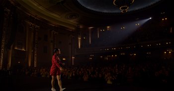 Movie still from “Ali Wong: Don Wong” (2022), directed by Nahnatchka Khan – A woman in a red dress is on the stage in front of an audience; Extreme Wide shot, Low angle