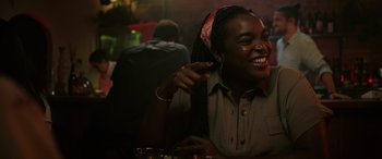 Movie still from “Alice, Darling” (2022), directed by Mary Nighy – A woman sitting at a table and smiling; Close Up shot, Over the shoulder angle