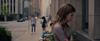 Movie still from “Alice, Darling” (2022), directed by Mary Nighy – A group of people sitting and standing on a sidewalk; Close Up shot, Over the shoulder angle