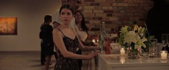 Movie still from “Alice, Darling” (2022), directed by Mary Nighy – A woman standing at a counter with a bottle of wine; Medium shot, Over the shoulder angle