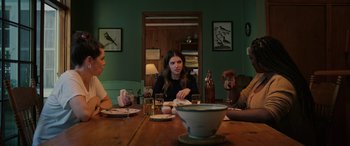 Movie still from “Alice, Darling” (2022), directed by Mary Nighy – A group of people sitting at a table with food; Medium shot, Over the shoulder angle
