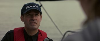 Movie still from “Alice, Darling” (2022), directed by Mary Nighy – A man wearing a police hat and a red jacket; Close Up shot, Over the shoulder angle