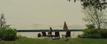 Movie still from “Alice, Darling” (2022), directed by Mary Nighy – A woman sitting on a lawn chair next to an umbrella; Extreme Wide shot, High angle