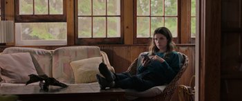 Movie still from “Alice, Darling” (2022), directed by Mary Nighy – A woman sitting on a couch looking at a cell phone; Medium shot, High angle