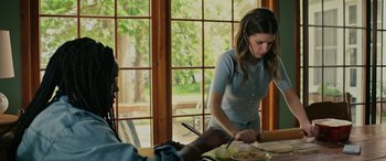 Movie still from “Alice, Darling” (2022), directed by Mary Nighy – A woman standing at a table cutting food; Medium shot, Over the shoulder angle