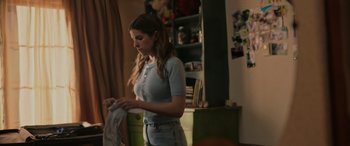 Movie still from “Alice, Darling” (2022), directed by Mary Nighy – A young woman in a blue shirt is looking at a shirt; Medium shot, Low angle