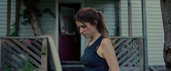 Movie still from “Alice, Darling” (2022), directed by Mary Nighy – A woman in a black tank top standing in front of a house; Close Up shot, Over the shoulder angle