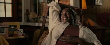 Movie still from “Alice, Darling” (2022), directed by Mary Nighy – A woman smiles while holding a guitar in her arms; Medium shot, High angle