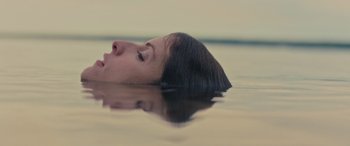 Movie still from “Alice, Darling” (2022), directed by Mary Nighy – A woman floating on top of a body of water; Close Up shot, Overhead angle