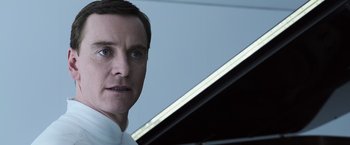 Movie still from “Alien: Covenant” (2017), directed by Ridley Scott – A person wearing a white shirt near a piano; Close Up shot, Low angle