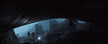 Movie still from “Alien: Covenant” (2017), directed by Ridley Scott – A group of people standing inside of a cave; Wide shot, Low angle