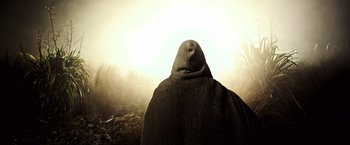 Movie still from “Alien: Covenant” (2017), directed by Ridley Scott – A person wearing a hooded cloak in a field; Close Up shot, Low angle