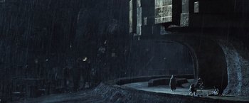 Movie still from “Alien: Covenant” (2017), directed by Ridley Scott – A penguin standing in the rain in front of a building; Extreme Wide shot, Low angle