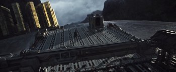 Movie still from “Alien: Covenant” (2017), directed by Ridley Scott – A man standing on top of a building near a mountain; Extreme Wide shot, High angle