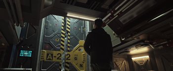 Movie still from “Alien: Covenant” (2017), directed by Ridley Scott – A man standing in front of a wall with yellow signs on it; Wide shot, Low angle