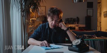 Movie still from “All About Gila” (2022), directed by Arturo González-Campos – A man sitting at a table talking on the phone; Medium shot, Low angle