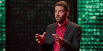 Movie still from “All About Gila” (2022), directed by Arturo González-Campos – A man in a red shirt and black jacket talking; Close Up shot, High angle