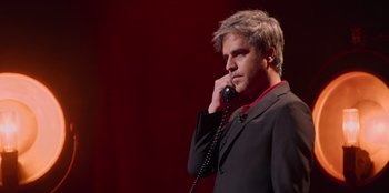 Movie still from “All About Gila” (2022), directed by Arturo González-Campos – A man talking on a phone while wearing a suit; Close Up shot, Low angle