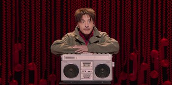Movie still from “All About Gila” (2022), directed by Arturo González-Campos – A man sitting in front of an old fashioned radio; Medium shot, Low angle