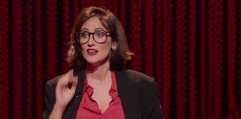 Movie still from “All About Gila” (2022), directed by Arturo González-Campos – A woman in a red shirt and black jacket is talking; Close Up shot, Over the shoulder angle