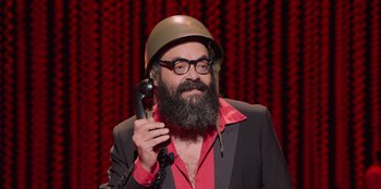 Movie still from “All About Gila” (2022), directed by Arturo González-Campos – A man with a beard wearing a helmet and talking on a phone; Close Up shot, Low angle