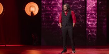 Movie still from “All About Gila” (2022), directed by Arturo González-Campos – A man standing on a stage with his hands in his pockets; Wide shot, Low angle